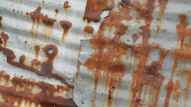 Heavily rusted corrugated metal zinc sheet with orange brown rust holes and corrosion texture industrial grunge background