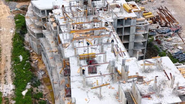 Construction workers building concrete floor reinforcement on high angle. High angle view of laborers working on the reinforced concrete deck of a building under construction.
