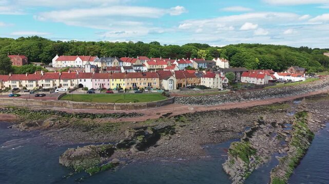 Aerial view of the picturesque coastal village of West Wemyss, featuring colorful traditional houses along the rocky shoreline of Fife, Scotland