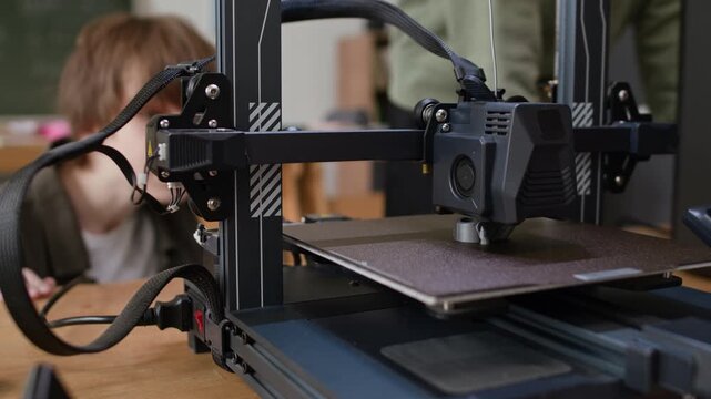 Low angle close up shot of teenage students enthusiastically observing 3D printing process during modeling class in school
