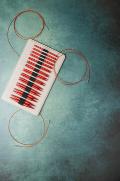 Set of interchangeable, circular knitting needles on green surface.