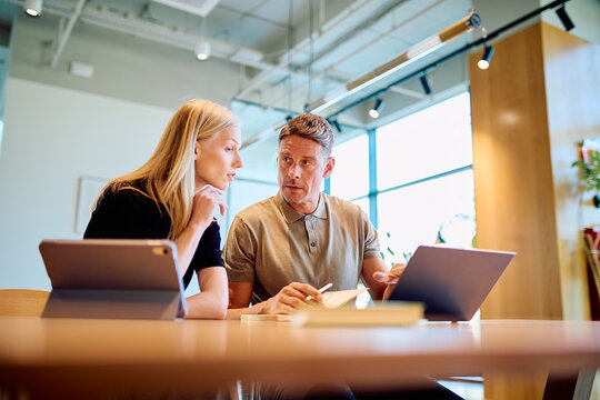 Business colleagues collaborating on a project, discussing ideas and planning work using modern technology in a bright office