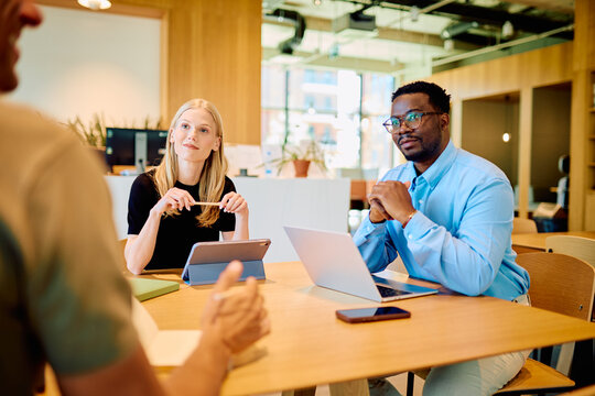 Diverse business professionals conducting a meeting, discussing ideas and collaborating on projects in a modern coworking space