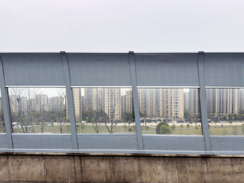 Apartment towers and urban parkland view through road sound barriers in China