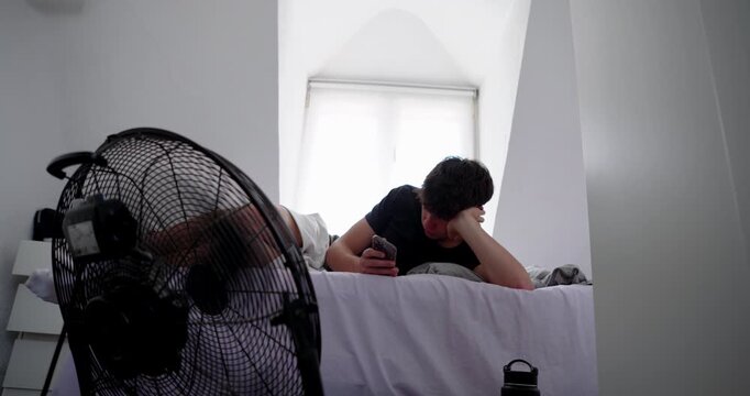 Man tired from heat in front of a fan