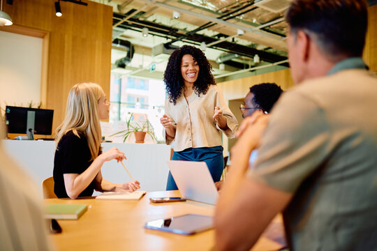 Multicultural business professional leading a team meeting, discussing ideas and collaborating in a contemporary office workspace