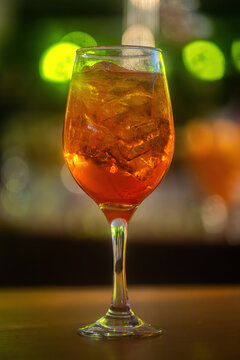 An aperol spritz drink on a glass at a lively bar during the evening with defocused background