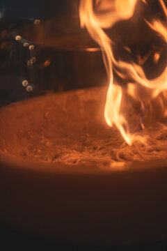 Pasta preparation with chef using torch at restaurant during evening service