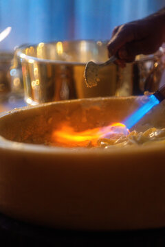 Pasta preparation with chef using torch at restaurant during evening service