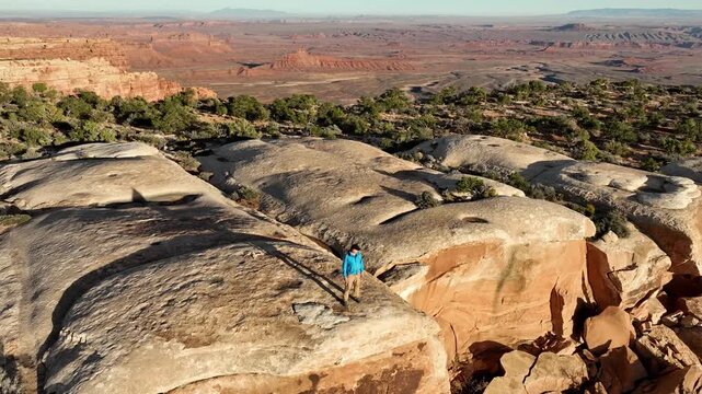 Aerial shot of a hiker walking along the incredible cliffs and rock formations at the edge of Cedar Mesa in Southern Utah.