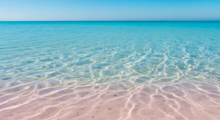 Obraz premium Crystal Clear Turquoise Ocean Water Gently Washing Onto Pink Sand Beach Under Bright Blue Sky
