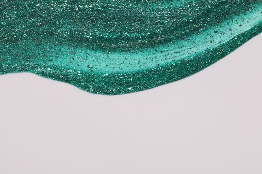 Green glitter nail polish on white background, top view. Space for text