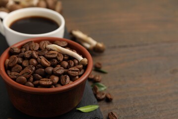Fototapeta premium Cup of coffee, beans and mushrooms on wooden table, closeup. Space for text