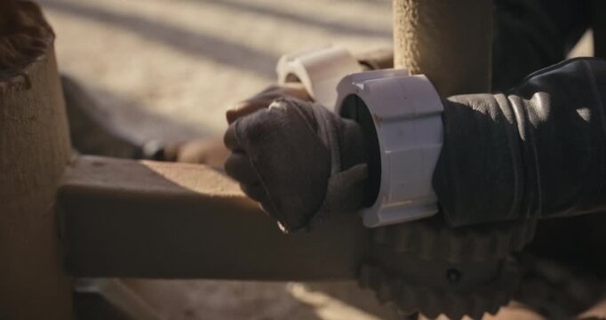 Dirty, female adventurer trying to escape handcuffs in desert sci-fi area - closeup