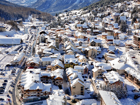 Aerial view of the snow-covered alpine village of Montgenevre featuring traditional chalets and a church tower in the French Alps Montgenevre, Provence-Alpes-Cote d, France.