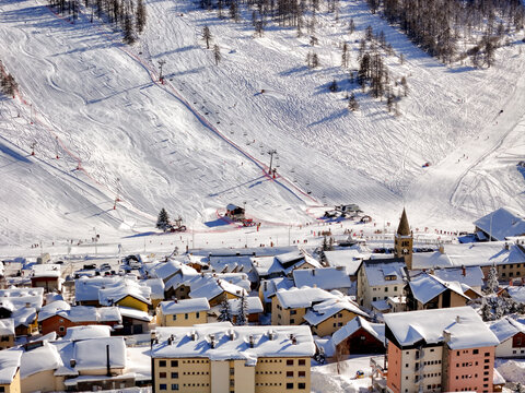 Aerial view of the Montgenevre ski resort village featuring snow-covered rooftops and mountain slopes with chairlifts in Montgenevre, Provence-Alpes-Cote d'Azur, France.