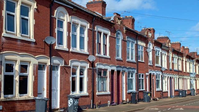 Traditional British terraced houses, red brick Victorian residential street, classic UK suburb architecture with wheelie bins and satellite dishes