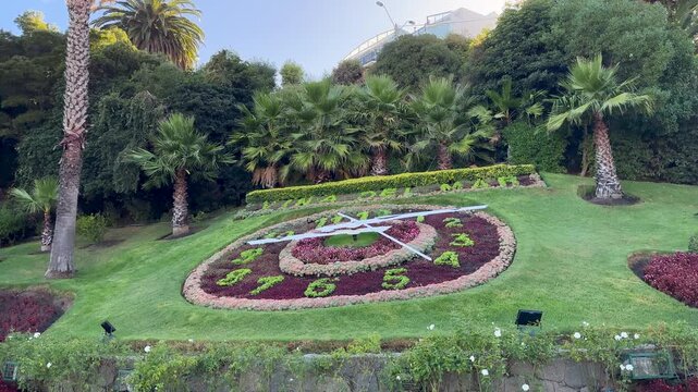Close-up video of the iconic Vina del Mar flower clock showing the movement of its hands over a vibrant floral dial in a beautiful public park setting