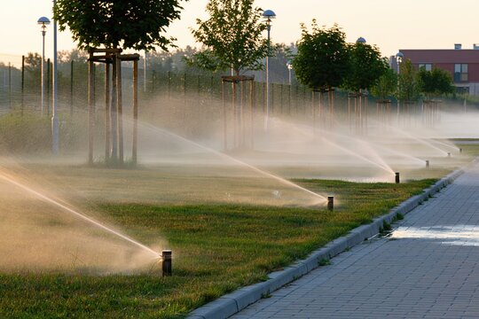 Automatic Irrigation Sprinklers Watering Green Lawn in Modern Residential Area