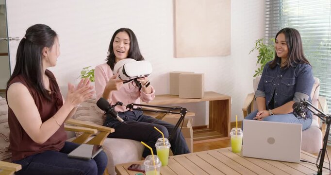 Diverse female hosts opening cardboard box in studio, lifting white headset with mics recording