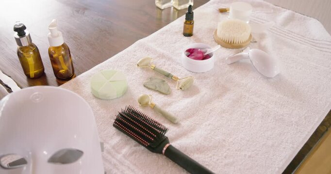 Slow camera is panning right, revealing skincare and hair tools on towel for home spa display