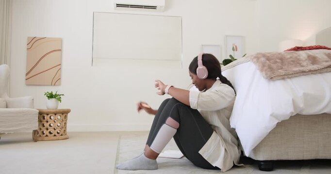 African woman in bedroom pink headset socks checking watch taking tablet reading texts, copy space