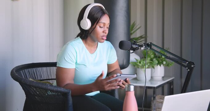 African American woman starting podcast in home studio, speaking into boom-mic, reading tablet