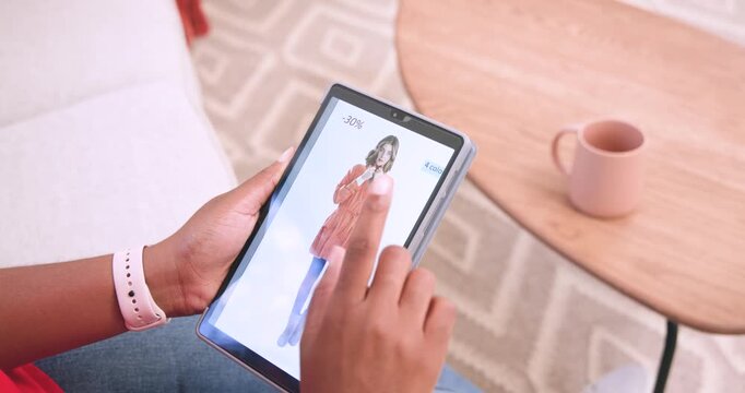 Adult woman sitting on couch in living room seeing sale label on tablet, swiping to order