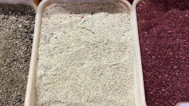 Bulk spice containers filled with black pepper white pepper and deep red sumac seasoning displayed at market for gourmet cooking and healthy cuisine.