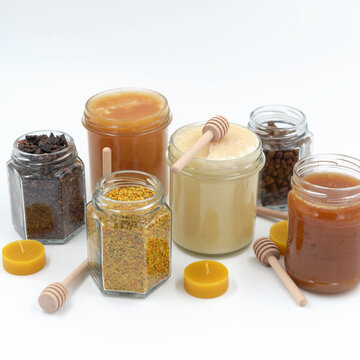 Assorted bee products in glass jars on white background
