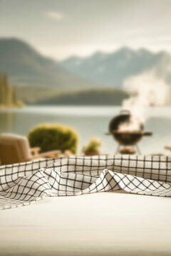 Wooden table with clean copy space for product placement and relaxing summer atmosphere with blurred summer picnic background.