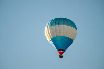 Fototapeta premium Blue and white hot air balloon floating against clear sky.