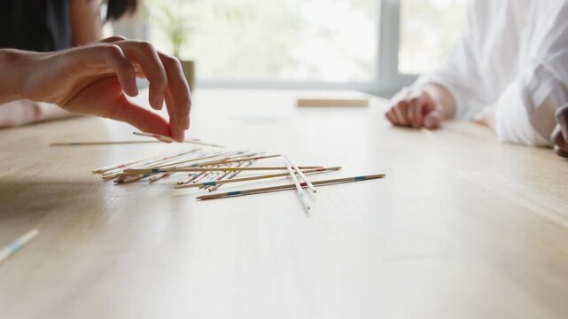 Close-up shot of hands of Diverse office team enjoys a lively Mikado board game session during their midday break, fostering fun, unity, and strong collaboration