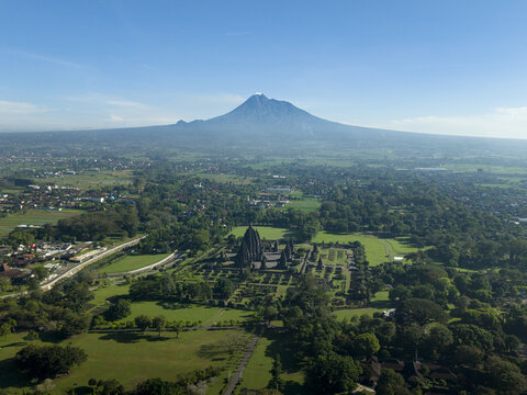 Aerial view of Prambanan Temple complex with Mount Merapi volcano in the background under a clear blue sky Kecamatan Prambanan, Daerah Istimewa Yogya, Indonesia.