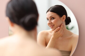 Naklejka premium Smiling woman with healthy skin near mirror at home
