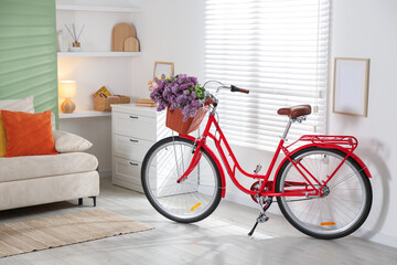 Fototapeta premium Bicycle with basket of beautiful lilac flowers indoors