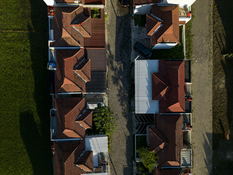 Aerial view of Sadari Villa Prambanan featuring traditional red-tiled rooftops and a narrow street adjacent to lush green fields in Kecamatan Prambanan, Jawa Tengah, Indonesia.
