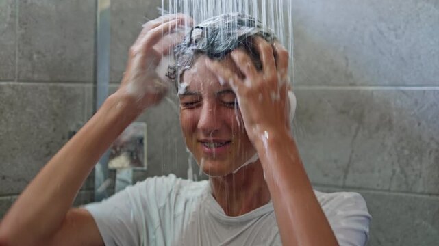 A teenage boy washes his hair with shampoo in the shower. Teen hygiene