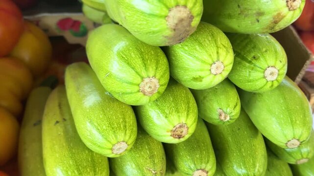 Natural zucchini squash stacked in market display with fresh green texture and healthy farm vegetable concept for organic food shopping.