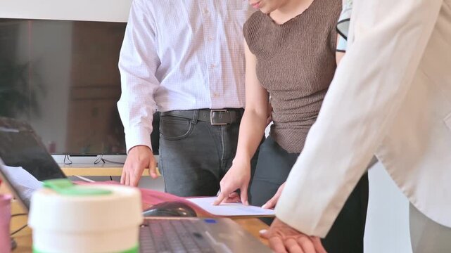 Three Colleagues Collaborating Over Documents in a Bright Office Business Meeting.