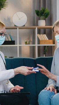 Healthcare concept where likable qualified adult medical worker in protective mask checking indicators of oxygen blood test in sick female patient applying pulse oximeter