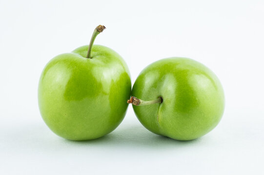 Two fresh green plums on white background