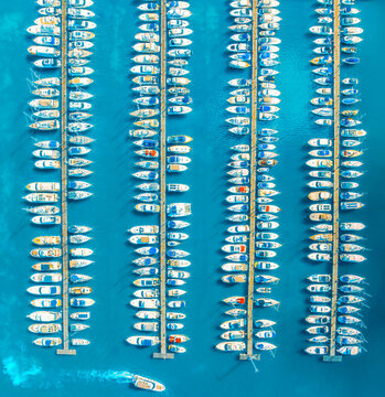 Aerial drone view of boats and luxury yachts in dock at sunset in summer in Krk island, Croatia. Colorful landscape with sailboats and motorboats in blue sea, jetty. Top down view of marina. Harbour