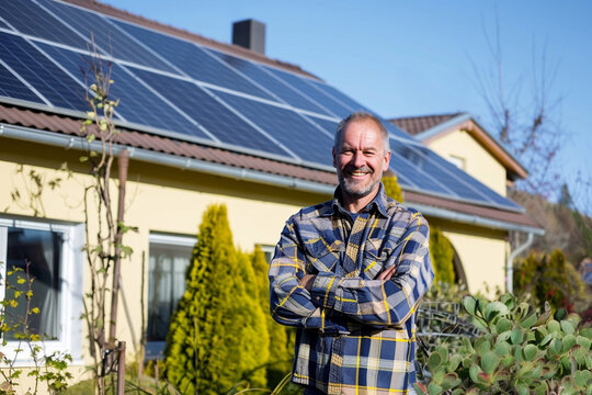 Happy Homeowner with Solar Panels Standing Outside Modern Energy Efficient House