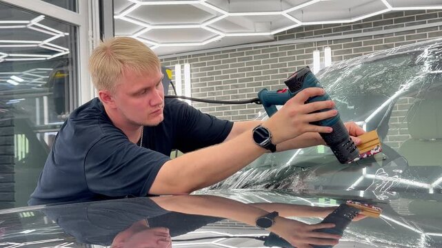 Car wrapping. Windshield protection. A man in the process of tinting the windshield. The concept of love for cars and protection. The process of installing the PPF on the windshield of a car. 