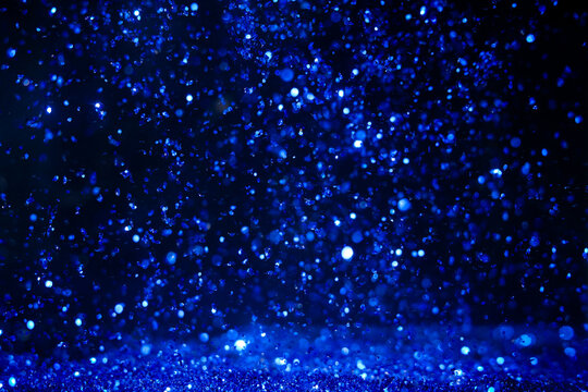 Drops of water create blue sparkles in the dark setting during nighttime