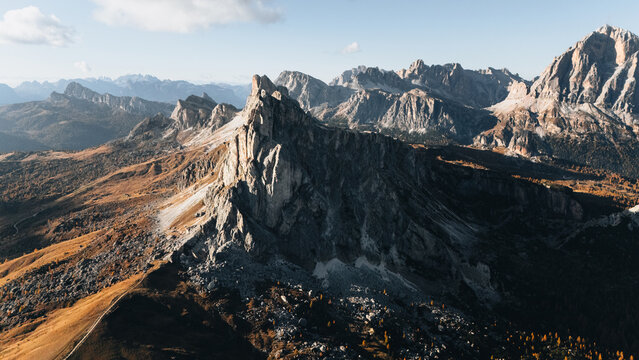 Aerial view of the majestic Passo Giau mountain pass with jagged peaks and rocky slopes under a clear sky in the Dolomites, Colle Santa Lucia, Veneto, Italy.