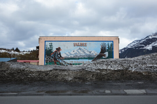 Snow built up on a mural featuring a gold panner and bald eagle in downtown Valdez, Alaska, May 2022