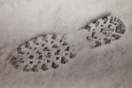 Winter boot footprints in fresh snow on sidewalk as evidence