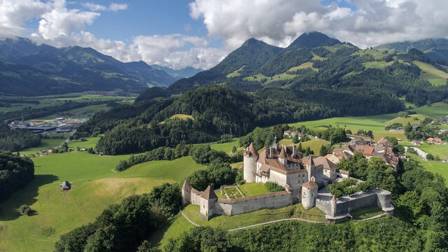 Gruyeres, Switzerland - 14 May 2026: Aerial view of Gruyeres Castle on a hilltop with its medieval towers, stone walls, and the surrounding Swiss Alps under a dramatic sky.